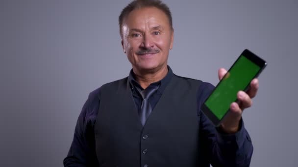 Closeup veselá staré kavkazské člověka pomocí tabletu a ukazuje greenscreen k fotoaparátu, zatímco s úsměvem — Stock video