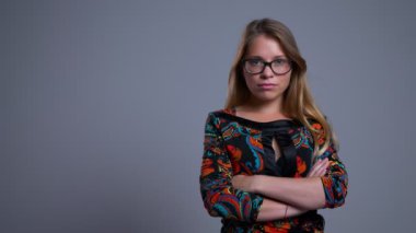 Kollarını göğüs üzerinde geçti ve kameraya bakarak olan gözlüklü genç emin beyaz kadın portresi portre