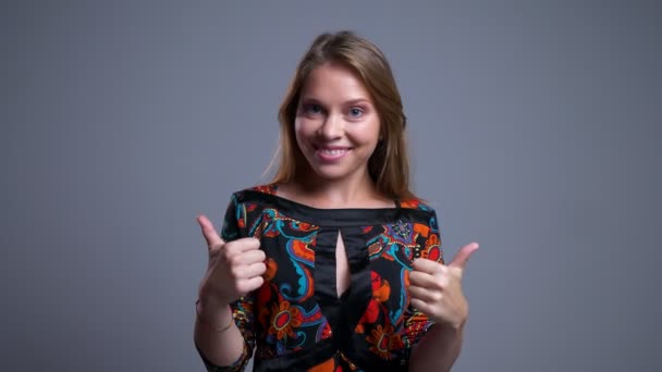 Portret zbliżenie atrakcyjny młody kaukaski kobieta uśmiechając się i pokazując kciuki do góry patrząc na kamery — Wideo stockowe