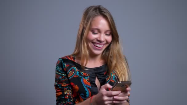 Крупним планом портрет молодої весела біла жінка переглядає по телефону і щасливо сміється — стокове відео