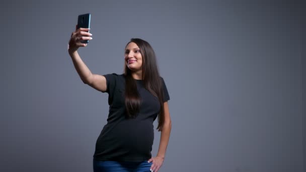 Nahaufnahme Porträt einer schwangeren jungen kaukasischen Frau, die Selfies am Telefon macht und Spaß hat — Stockvideo