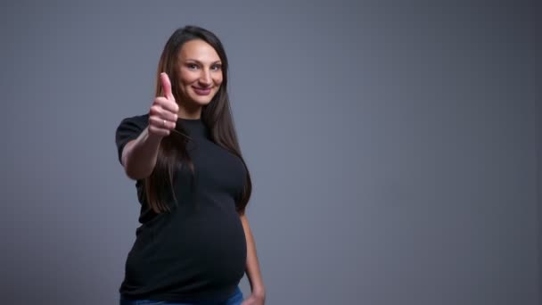 Primer plano retrato de la mujer caucásica joven embarazada mostrando el pulgar hacia arriba y sonriendo mientras mira a la cámara — Vídeos de Stock
