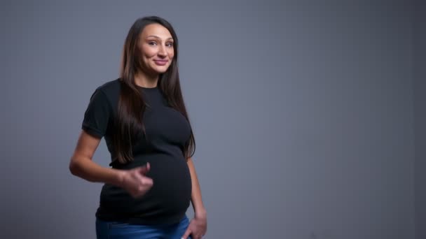 Крупный план портрета беременной веселой белой женщины, показывающей большой палец и смотрящей в камеру — стоковое видео