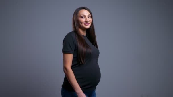 Nahaufnahme Porträt einer schwangeren fröhlichen kaukasischen Frau, die sich dreht und lächelnd in die Kamera blickt — Stockvideo