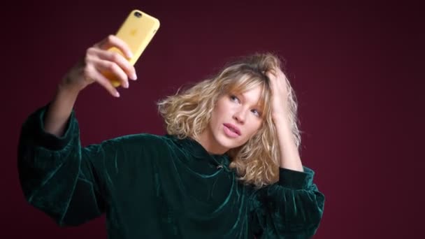 Primer plano retrato de joven atractiva mujer caucásica tomando selfies en el teléfono delante de la cámara — Vídeo de stock