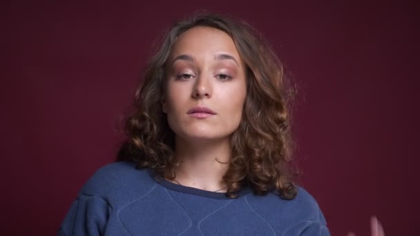 Portret zbliżenie młoda atrakcyjna kobieta kaukaski ustalania jej włosy, podnosząc brwi i kiwając głową patrząc na kamery — Wideo stockowe