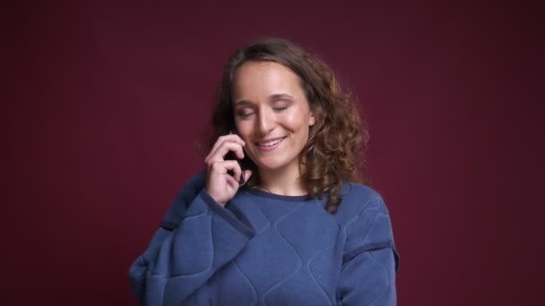 Primer plano retrato de joven alegre mujer caucásica hablando por teléfono y sonriendo felizmente — Vídeo de stock