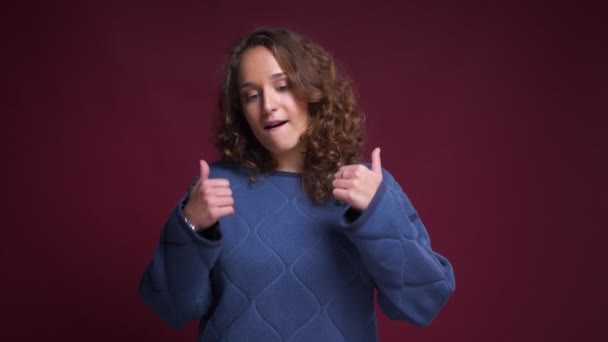 Primer plano retrato de joven atractiva mujer caucásica sonriendo mostrando los pulgares hacia arriba y mirando a la cámara — Vídeos de Stock