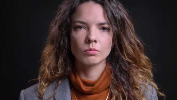 Nahaufnahme Porträt einer schönen jungen kaukasischen Frau in formalen Kleidern, die mit neutralem Gesichtsausdruck direkt in die Kamera blickt — Stockvideo