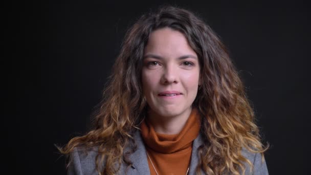 Closeup portrait of tempting attractive female looking at camera smiling and biting her lip with the background isolated on black — Stock Video