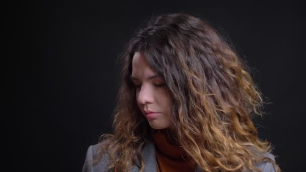 Retrato de cerca de una joven hembra caucásica aburrida mirando a los lados y arriba con el fondo aislado en negro — Vídeos de Stock