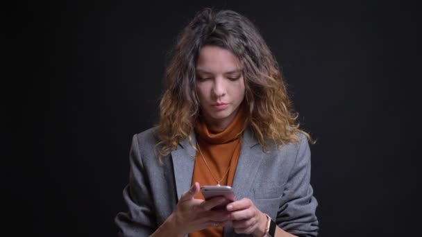 Retrato de la mujer caucásica atractiva moderna escribiendo en el teléfono y siendo reflexivo, molestando con un teléfono inteligente — Vídeos de Stock