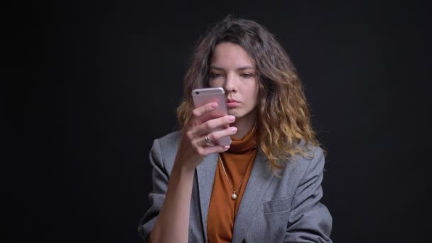 Κινηματογράφηση σε πρώτο πλάνο porttait σύγχρονο νεαρό θηλυκό περιήγησης στο τηλέφωνό της κοιτάζοντας φωτογραφική μηχανή και το γέλιο — Αρχείο Βίντεο