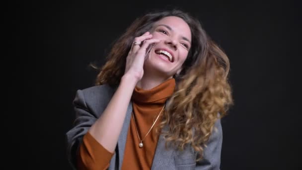 Крупный план портрета красивой молодой женщины, разговаривающей по телефону и счастливо смеющейся — стоковое видео