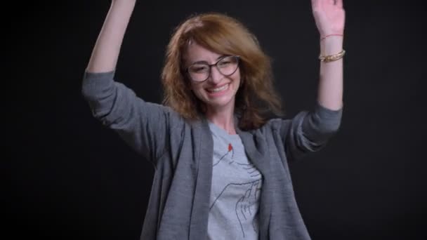 Closeup portrait of cheerful middle-aged female in glasses having fun with the background isolated on black — Stock Video