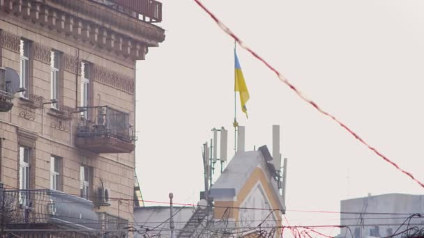 Street shot de edificio con bandera ucraniana ondeando en el viento sobre el cielo y el fondo de la ciudad — Vídeos de Stock