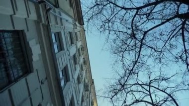 Dolly shot from bottom of city buildings on left side slowly moving with camera.