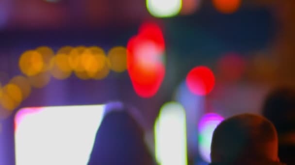 カラフルな街ライト背景を夜にしっかりと歩行のシルエットのぼやけショット. — ストック動画