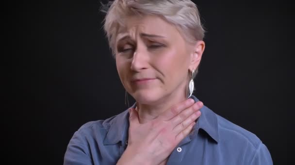 Крупный план портрета больной взрослой белой женщины, кашляющей больным горлом и смотрящей в камеру — стоковое видео