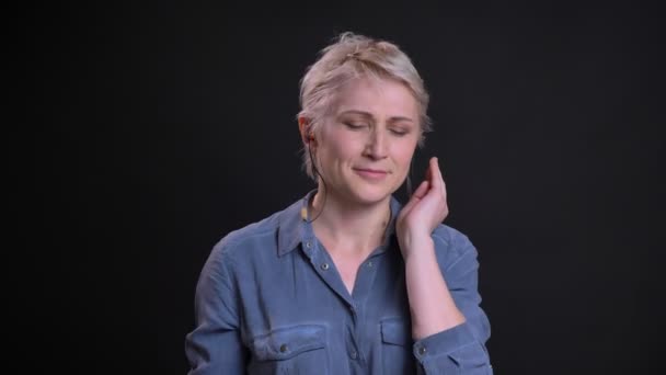 Крупним планом портрет привабливої кавказької жінки в вібрує посміхаючись і слухаючи музику — стокове відео