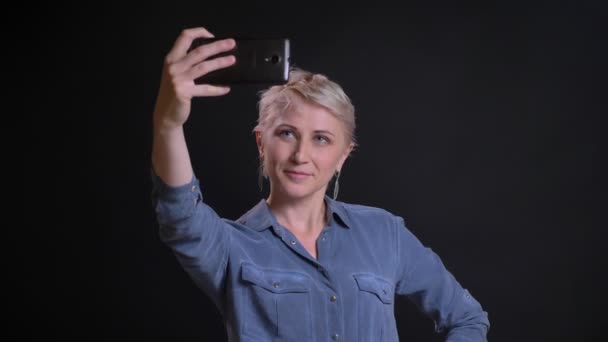 Primer plano retrato de atractiva mujer caucásica tomando selfies en el teléfono sonriendo y posando — Vídeos de Stock
