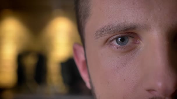 Gros plan demi-visage pousse de jeune caucasien visage masculin avec les yeux bleus regardant directement la caméra — Video