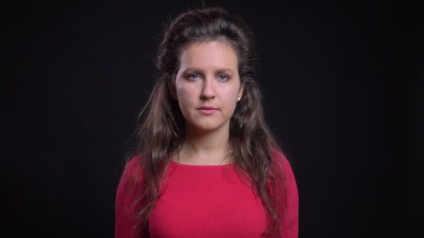 Portret van een Kaukasische vrouw in het rood verhoogt haar hoofd en rustig kijken in de camera op zwarte achtergrond. — Stockvideo