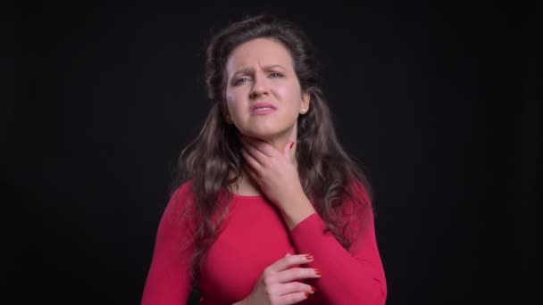 Retrato de mujer caucásica en rojo con dolor de garganta sobre fondo negro . — Vídeo de stock