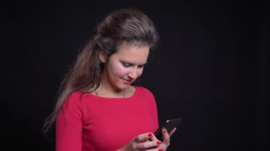 Portre profil gülümseyerek smartphone siyah arka plan üzerine içine izlerken kırmızı beyaz kadın.