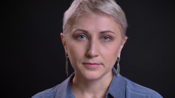 Closeup portret van mooie Kaukasische vrouwelijke gezicht kijken recht op de camera met de achtergrond geïsoleerd op zwart — Stockvideo