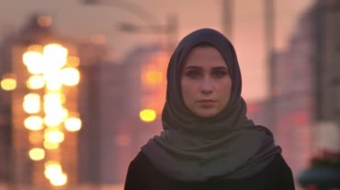 Kentsel şehir ve arka plan üzerinde parlayan ile sol ve ardından kamera bakarak hijab genç çekici Müslüman kadın portresi portre