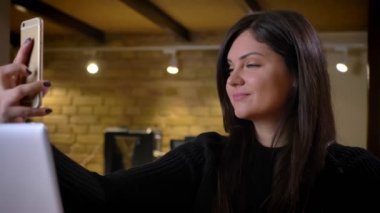Telefonda selfies alarak ve laptop önünde oturma gülümseyen yetişkin beyaz mutlu işkadını closeup portresi