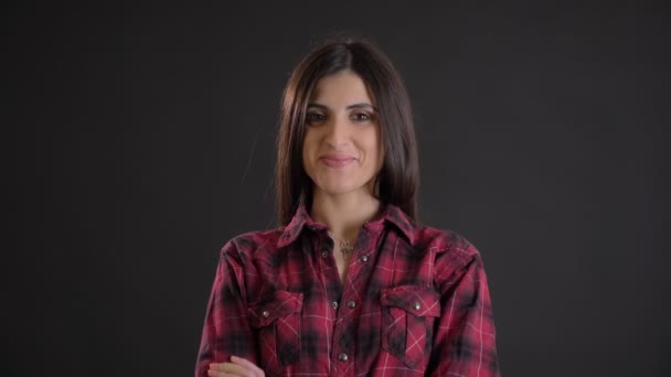 Portrait of caucasian long-haired brunette girl with arms crossed modestly smiling into camera on black background. — Stock Video