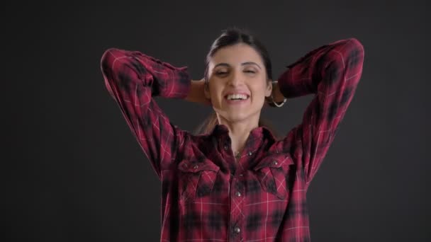 Porträt eines kaukasischen langhaarigen brünetten Mädchens, das in die Kamera lacht und ihr Haar auf schwarzem Hintergrund schüttelt. — Stockvideo