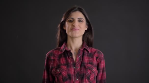 Retrato de morena caucásica de pelo largo con mucho gusto acogiendo a la cámara y agitando su mano sobre fondo negro . — Vídeos de Stock