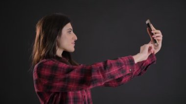 Selfie-fotoğrafları yapma genç ve güzel beyaz uzun saçlı kız portresi siyah arka plan üzerine smartphone kullanarak.