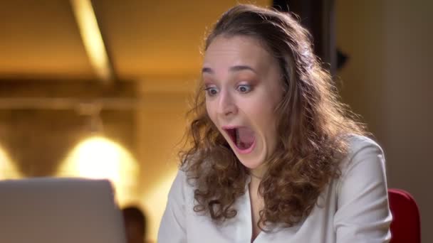 Close-up retrato de jovem de cabelos encaracolados mulher fica extremamente feliz e beija laptop no escritório . — Vídeo de Stock