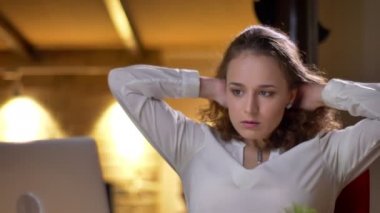 Genç kıvırcık saçlı kadın portresi yakın çekim bıkkın ve yorgun koltuğa uzanmış ve saçlarını ofiste sallayarak.