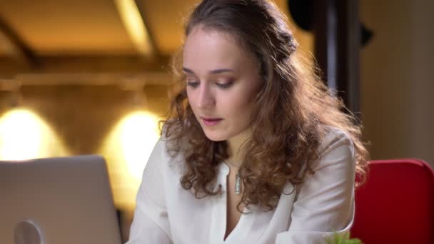 Curly-haired businesswoman का बंद-अप पोर्ट्रेट ध्यान से लैपटॉप के साथ काम कर रहा है अधिसूचना प्राप्त करता है और बहुत खुश हो जाता है . — स्टॉक वीडियो