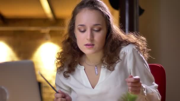 Portrait d'une jeune femme aux cheveux bouclés dansant joyeusement et jouant de la batterie invisible assise sur son siège au bureau . — Video