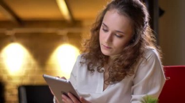 Cidden tablet izliyor ve kamera ofiste onun gözlerine yükselterek genç kıvırcık saçlı işkadını portresi.