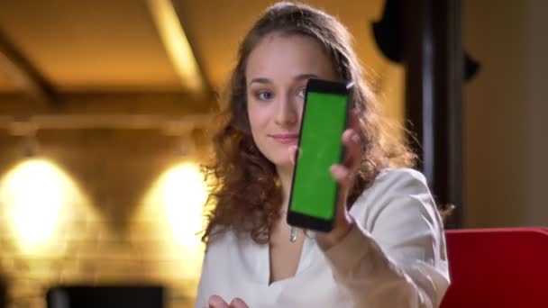 Close-up portret van jonge curly-haired zakenvrouw glimlachend tonen groen scherm van tablet naar camera. — Stockvideo