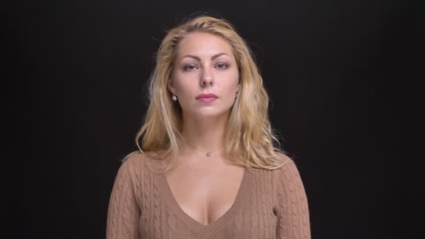 Portrait de belle femme caucasienne aux cheveux longs regardant calmement dans la caméra sur fond noir . — Video