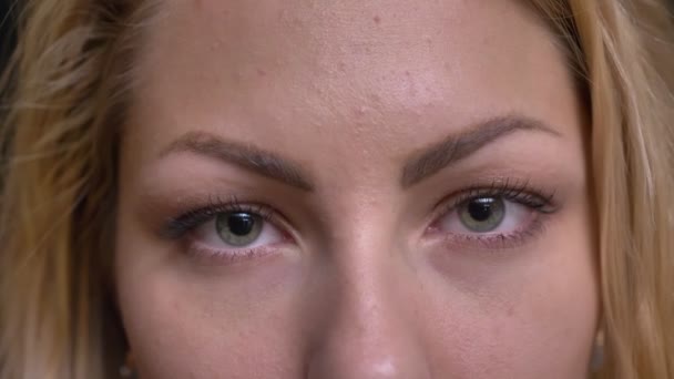 Close-up oog-portret van Kaukasische langharige vrouw serieus kijken naar de camera op zwarte achtergrond. — Stockvideo