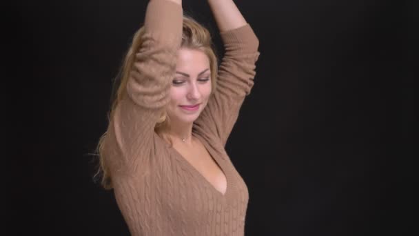 Portret van vrolijke Kaukasische langharige vrouw dansen vrolijk in de camera op zwarte achtergrond. — Stockvideo