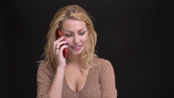 Retrato de bela mulher caucasiana de cabelos compridos sorrindo falando no smartphone no fundo preto . — Vídeo de Stock