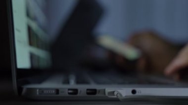 Bulanık yakın çekim shot el laptop ve smartphone koyu arka plan üzerinde çalışma.