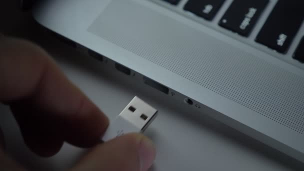 Nahaufnahme von Hand, die schnell weißes USB-Kabel in Laptop auf schwarzem Tischhintergrund einfügt. — Stockvideo