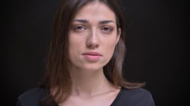 Yakın çekim portre Genç beyaz uzun saçlı esmer kız ağır kameraya siyah arka plan içine izlerken.