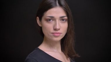 Yakın çekim portre Genç beyaz uzun saçlı esmer kız döner ve siyah arka plan üzerine kamera içine saatler.